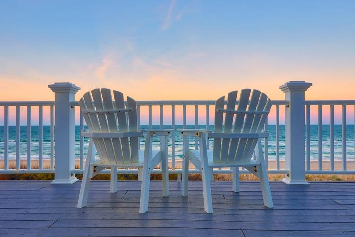 Two deck chairs on a vacation rental home on Hilton Head Island, looking out at sunrise over the ocean.